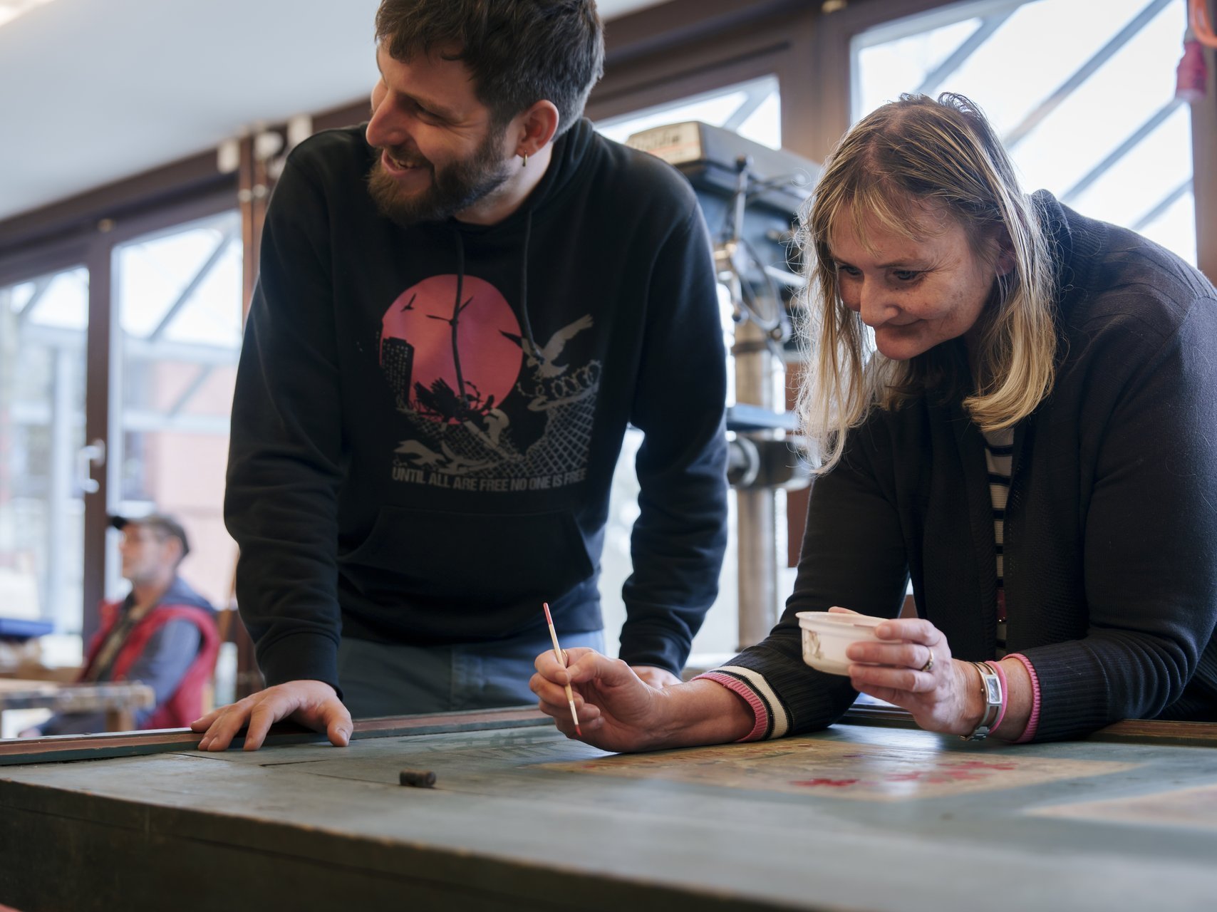 Mit sichtlichem Spaß arbeiten zwei Personen in der Schreinerwerkstatt.