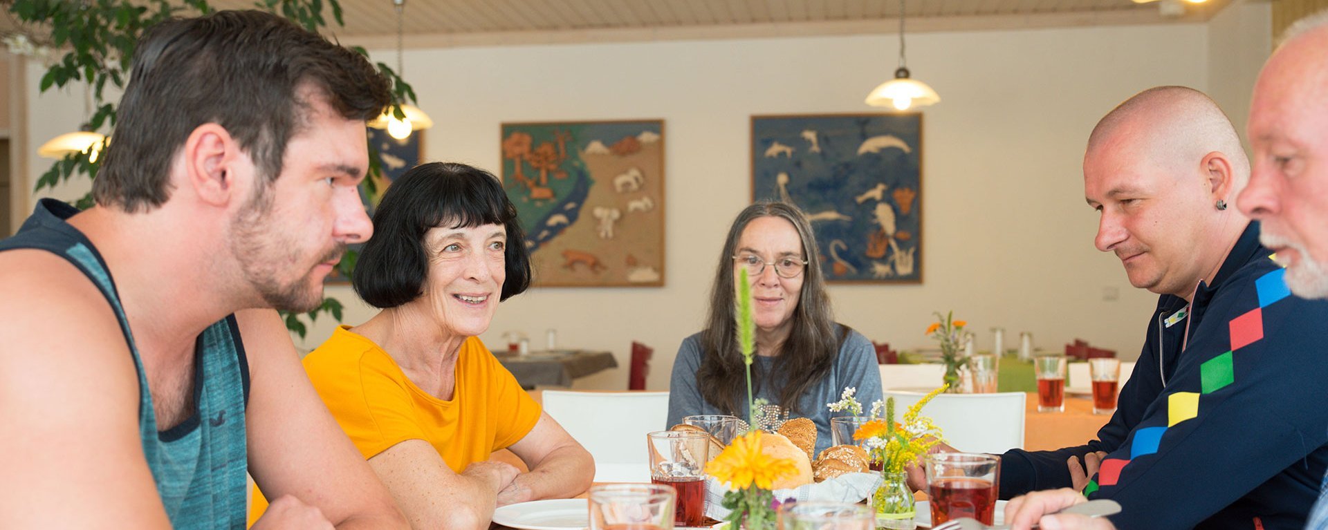 zwei ältere Frauen lächeln am reichlich gedeckten Frühstückstisch in die Kamera